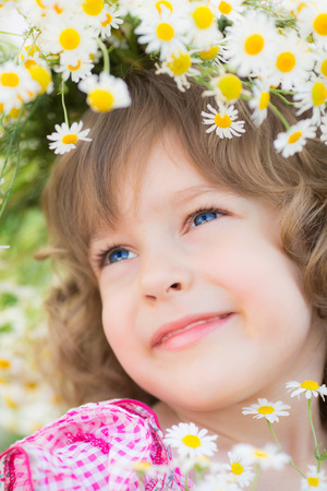 Happy child with daisy flowers outdoors in spring gardenの写真素材
