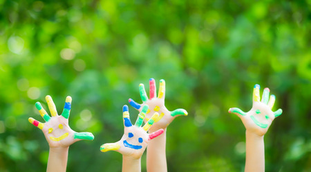 Happy child with smiley on hands against green spring background