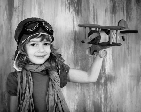 Black and white portrait of happy kid playing with toy wooden airplane indoorsの写真素材