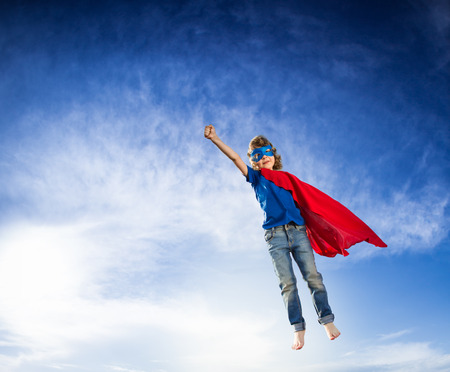 Superhero kid flying against dramatic blue sky backgroundの写真素材
