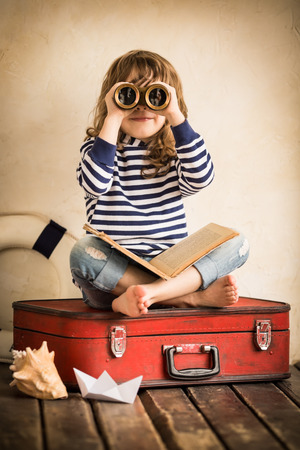 Funny kid playing with toy sailing boat indoors. Travel and adventure conceptの写真素材