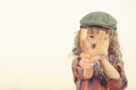 Child holding slingshot in hands against summer sky backgroundの写真素材