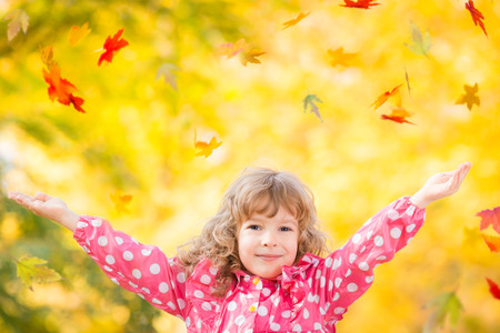 Happy child playing with leaves outdoors in autumn parkの写真素材