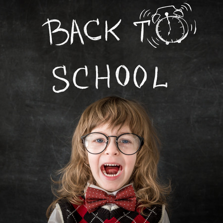 Smart kid in class. Happy child against blackboard. Education conceptの写真素材