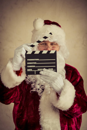 Santa Claus holding clapper against grunge wall background. Christmas holiday conceptの写真素材