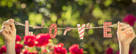 Letter LOVE in hands against spring green backgroundの写真素材