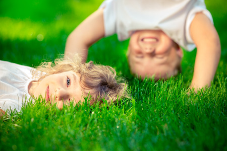 Happy children standing upside down on green grass. Smiling kids having fun in spring park. Healthy lifestyle conceptの写真素材