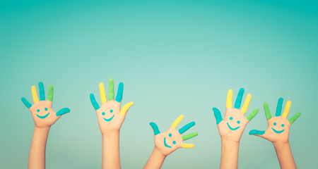 Happy people with smiley on hands against blue summer sky background Happy people with smiley on hands against blue summer sky background