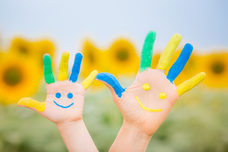 Happy family with smiley on hands against blue sky and yellow sunflower background Happy family with smiley on hands against blue sky and yellow sunflower background