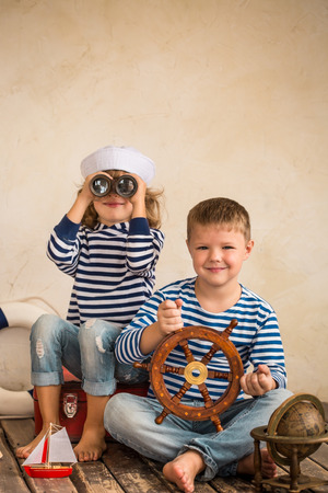 Children playing with vintage nautical things. Kids having fun at home. Travel and adventure concept. Retro toned imageの写真素材