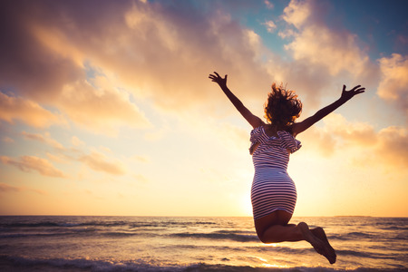Happy young woman jumping at the beach. Summer vacation conceptの写真素材