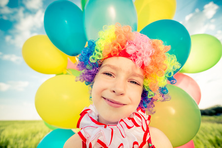 Happy child playing with colorful toy balloons outdoors.の写真素材