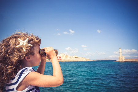 Sailor kid looking through the binoculars against blue sky backgroundの写真素材