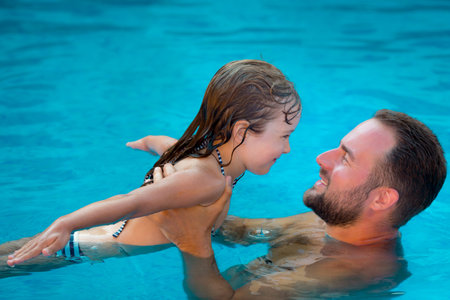 Happy child and father playing in swimming pool. Summer vacation concept