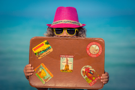 Happy child with vintage suitcase on the beach. Summer vacation and travel conceptの写真素材