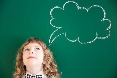 School kid in class. Happy child against green blackboard. Education concept