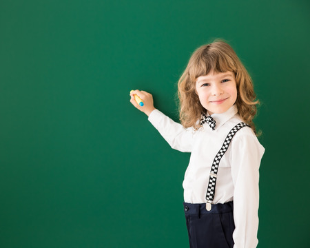 School kid in class. Happy child against green blackboard. Education conceptの写真素材