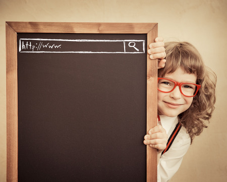 School kid in class. Happy child holding blackboard blank. Education concept