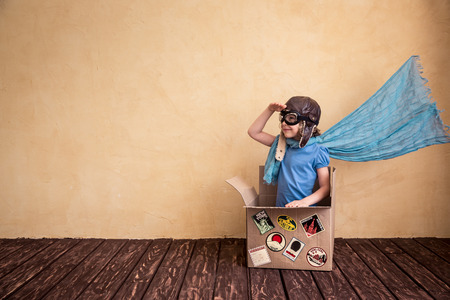 Happy child playing in cardboard box. Kid having fun at home