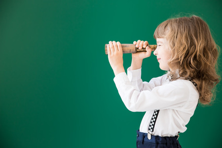 School kid in class. Happy child against green blackboard. Education conceptの写真素材