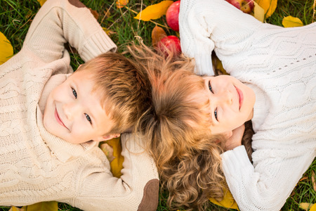 Happy children lying on fall leaves. Funny kids outdoors in autumn parkの写真素材