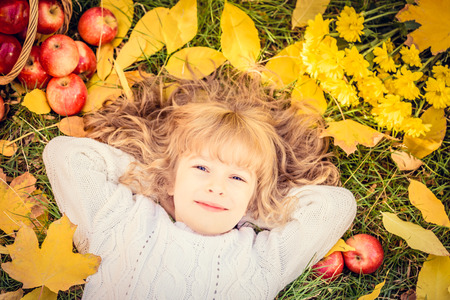 Happy child lying on fall leaves. Funny kid outdoors in autumn parkの写真素材