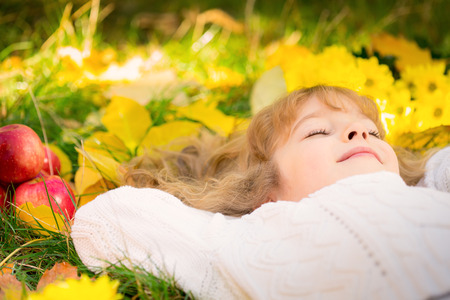 Happy child lying on fall leaves. Funny kid outdoors in autumn parkの写真素材