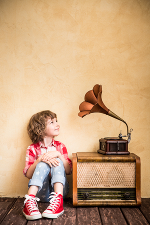 Kid listen music at home. Hipster child with retro vintage radioの写真素材