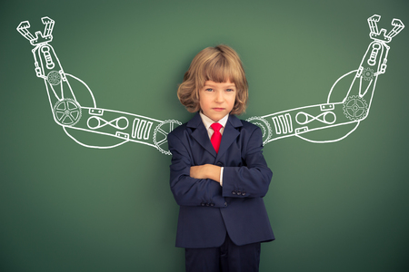 Kid with drawn robot hands against blackboard. Schoolchild in classの写真素材