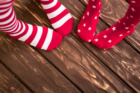 Feet wearing Christmas socks on wood floor. Happy family at home. Xmas holidays concept