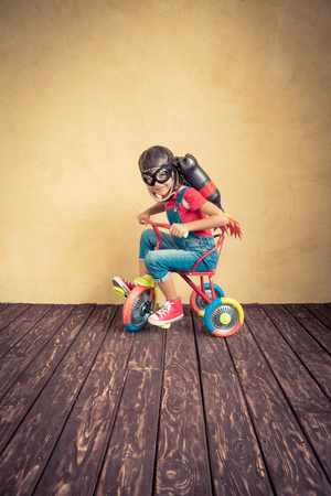 Kid with jet pack riding bike. Child playing at home. Success, leader and winner conceptの写真素材