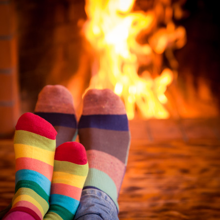 Father and kid's feet in Christmas socks near fireplace. Family relaxing at home. Winter holiday conceptの写真素材
