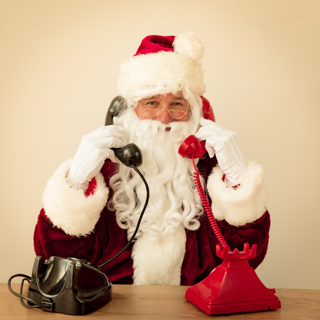 Santa Claus talking by phones. Christmas holiday conceptの写真素材