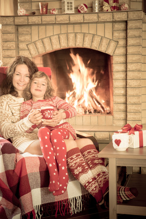 Woman and child at home near fireplace. Winter holiday conceptの写真素材