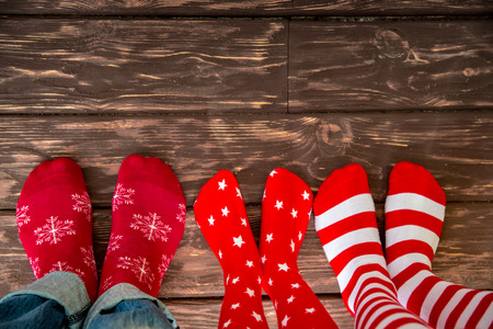 Feet wearing Christmas socks on wood floor. Happy family at home. Xmas holidays conceptの写真素材
