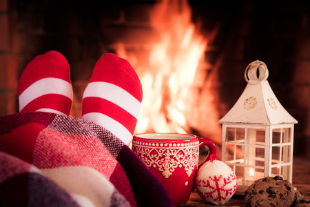 Woman at home. Feet in Christmas socks near fireplace. Relaxing and comfort. Winter holiday conceptの写真素材