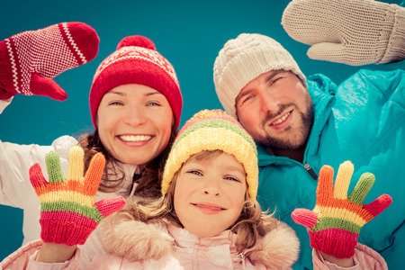 Happy family having fun outdoors in winter against blue sky backgroundの写真素材