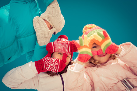Happy family having fun outdoors in winter against blue sky backgroundの写真素材