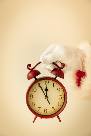 Santa Claus holding vintage alarm clock in hands. Christmas holiday conceptの写真素材