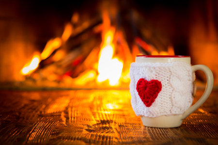 Cup of coffee near fireplace. Valentine's day at home. Winter holiday concept