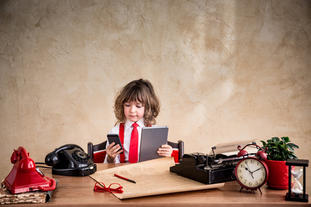 Portrait of child businessman in office. Kid holding gadgets. Communication in business conceptの写真素材