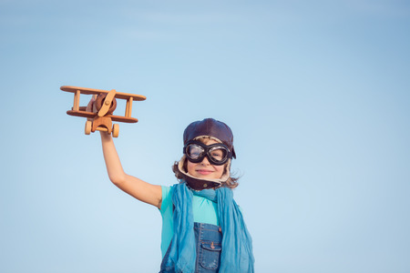 Happy kid playing with toy airplane against summer sky background. Travel conceptの写真素材