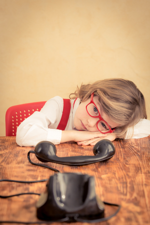 Sad child businessman with retro phone. Business communication conceptの写真素材