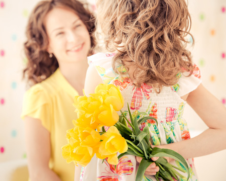 Woman and child with bouquet of flowers at home. Spring family holiday concept. Mother's dayの写真素材