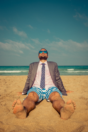 Portrait of funny businessman on the beach. Man having fun by the sea. Summer vacation and travel conceptの写真素材