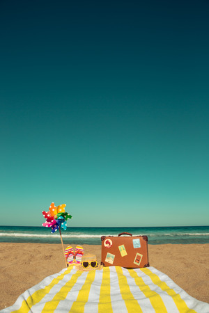 Vintage suitcase and beach items against blue sea and sky background. Summer vacation conceptの写真素材