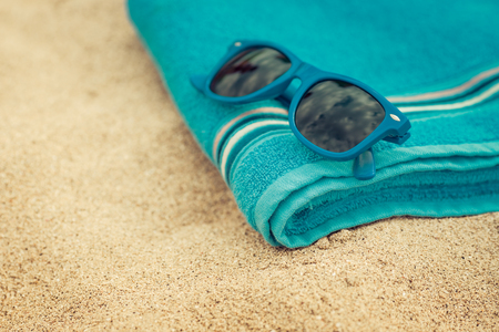 Towel and sunglasses on sandy beach against blue sea and sky background. Summer vacation conceptの写真素材
