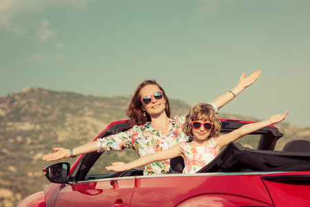 Happy family travel by car in the mountains. People having fun in red cabriolet. Summer vacation conceptの写真素材
