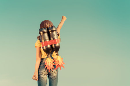 Kid with jet pack pretend to be superhero. Child playing in summer outdoors. Success, leader and winner conceptの写真素材