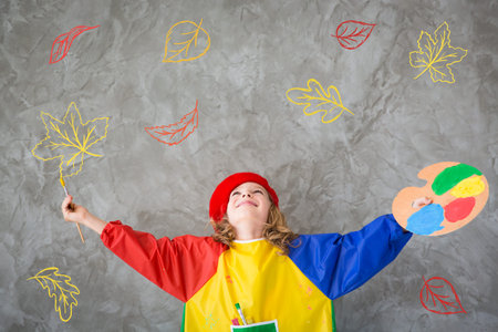 Happy child playing at home. Drawing autumn theme. Imagination and freedom conceptの写真素材